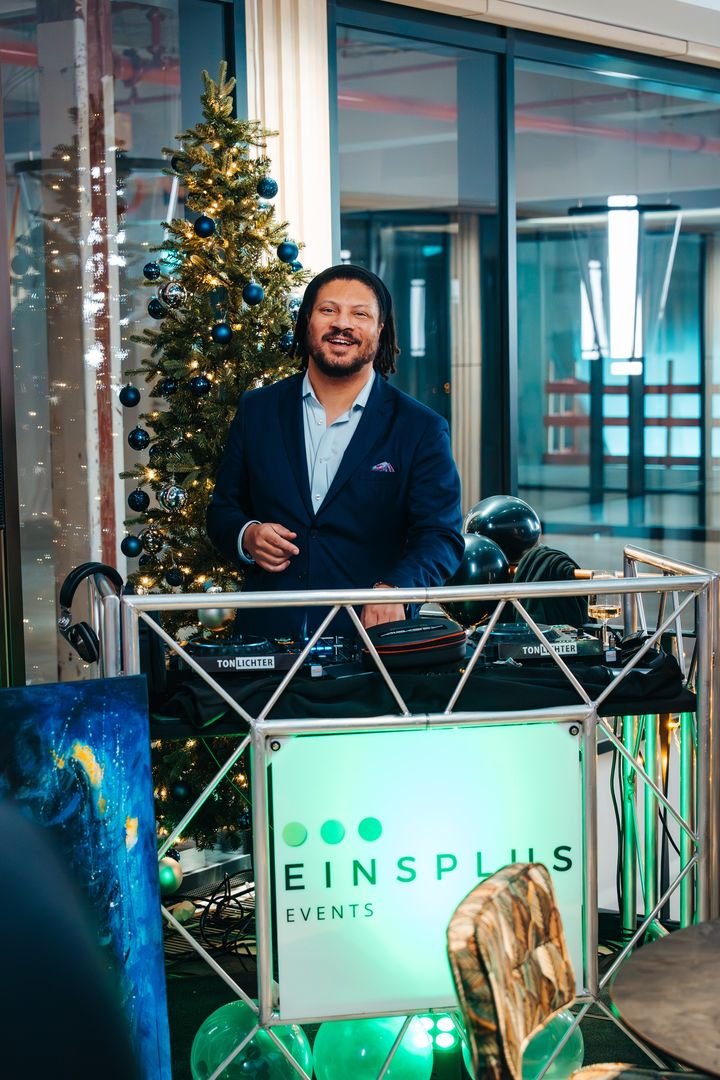 DJ am Pult neben einem Weihnachtsbaum