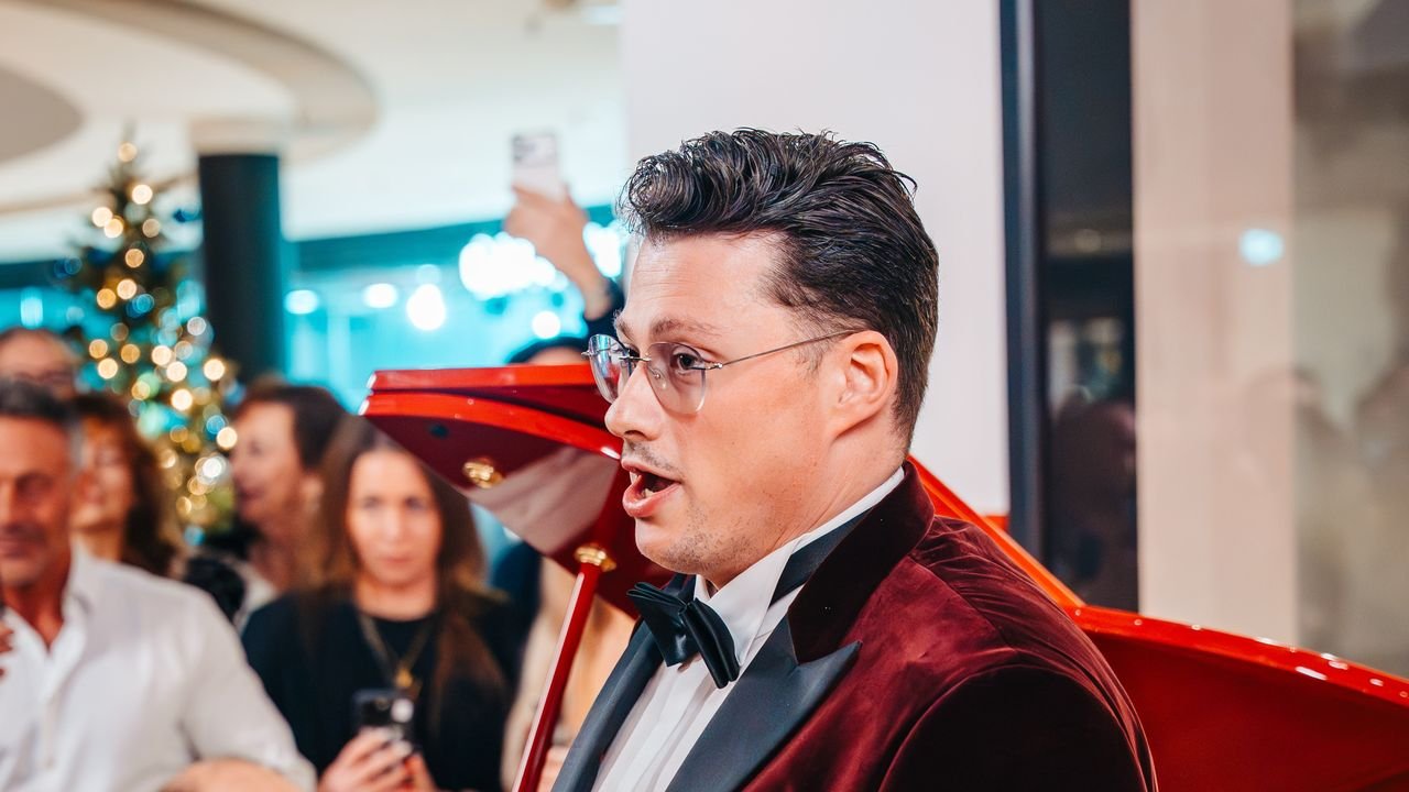 Sänger im roten Samtsakko vor einem roten Flügel bei einem Abend in der POSH BAR