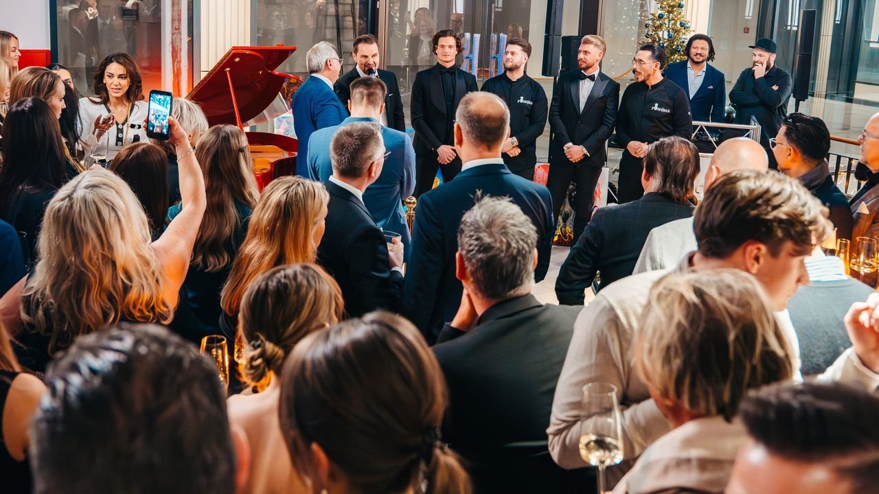 Begrüßung mit Mikrofon vor zahlreichen Gästen, daneben das POSH BAR Team