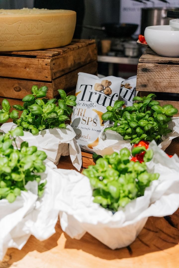 Auslage mit frischem Basilikum, Käselaib und Trüffelprodukten bei einem Empfang