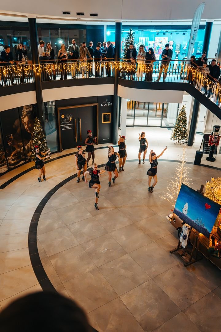 Tänzerinnen bei einer Showeinlage im Atrium der Galerie Luise, Gäste schauen von den Galerien zu