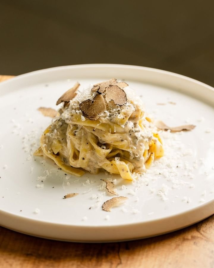 Tagliatelle mit frisch gehobeltem Trüffel auf weißem Teller